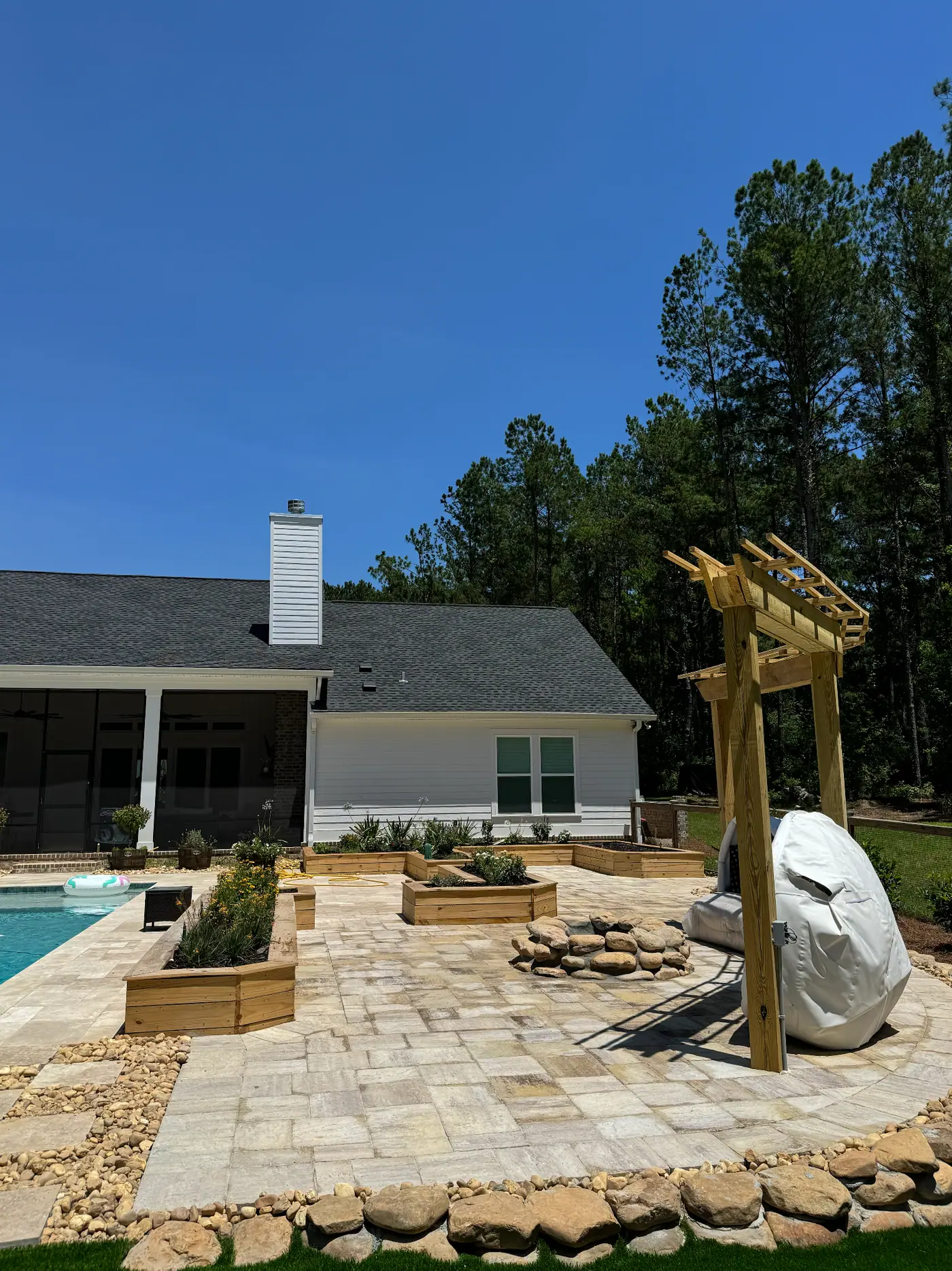 Dault poolside patio with raised planting beds and stone borders after installation